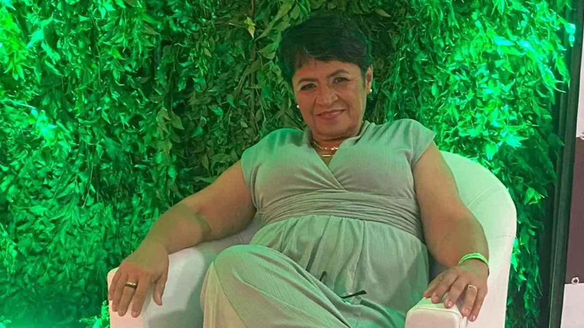 Foto da servidora pública do Eusébio, Maria Madalena Marques Matsunobu. Ela usa um vestido verde e está sentada em uma poltrona branca