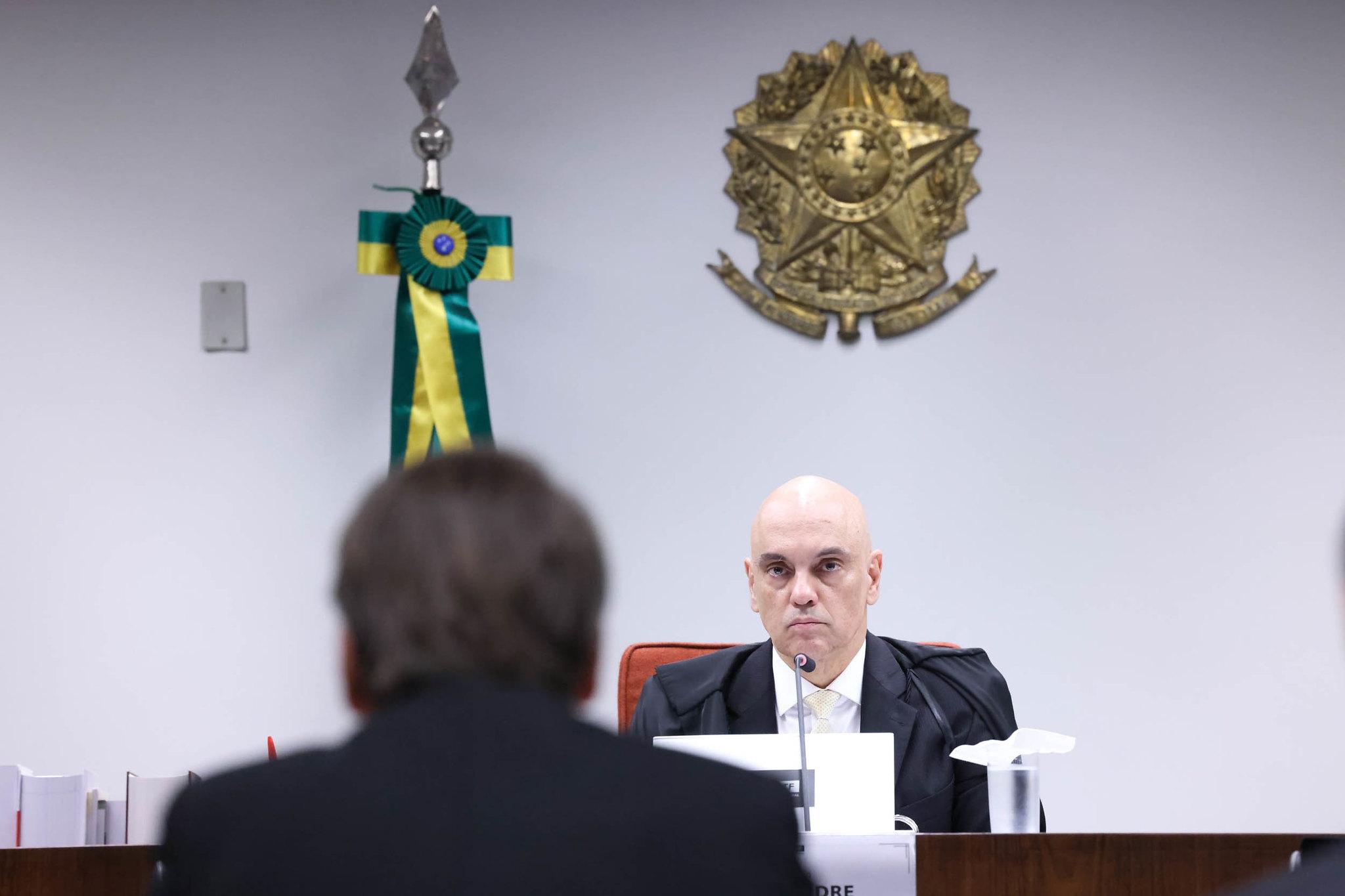 Jair Bolsonaro sentado à frente de Alexandre de Moraes no STF durante interrogatório