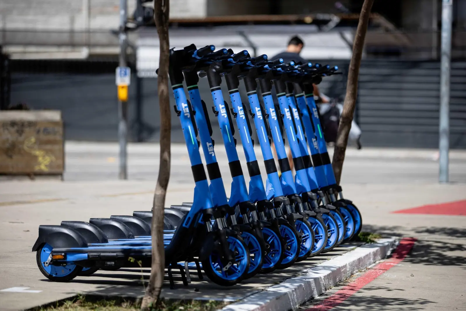Imagem mostra dez patinetes elétricos azuis com guidão preto enfileirados em uma calçada de Fortaleza