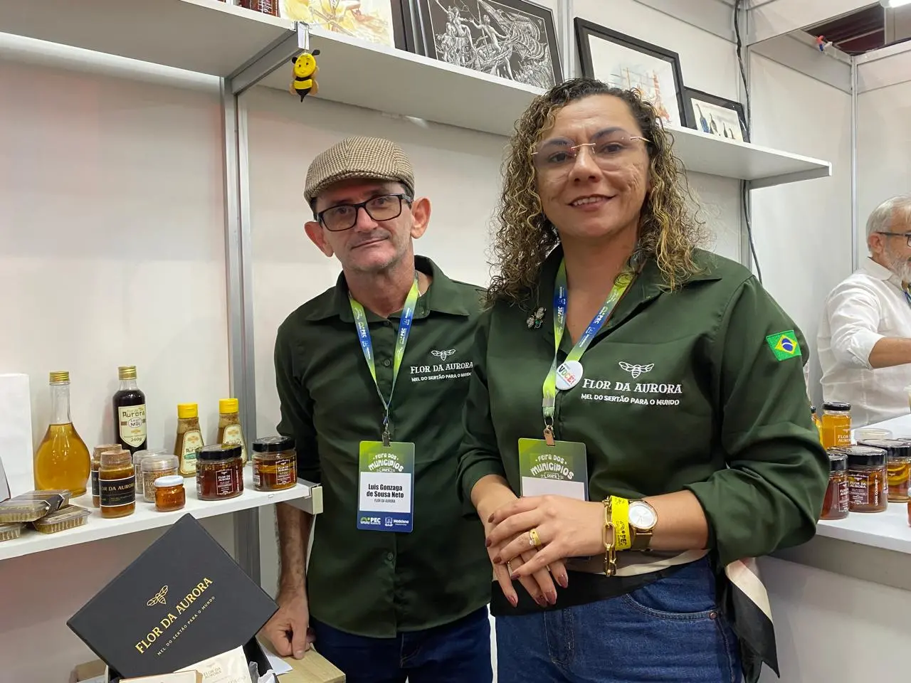 Imagem mostra uma mulher chamada Dina Pereira e o esposo, Luiz Gonzaga, com os produtos da marca Flor da Aurora