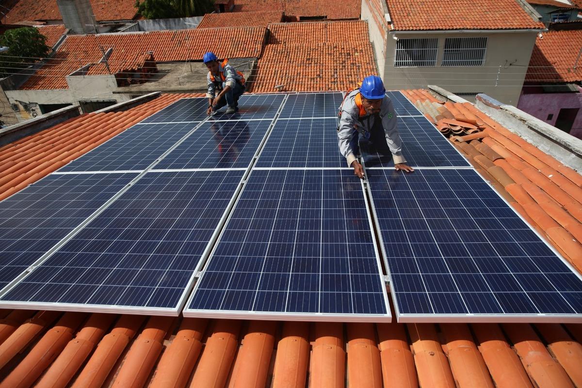 Dois homens estão em um telhado instalando paineis solares