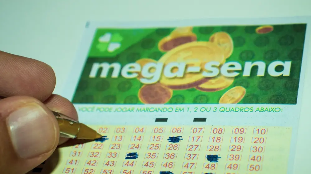 Pessoa marcando números em uma cartela de aposta de mega-sena, destacando a importância da loteria para sorteios e apostas no Brasil.
