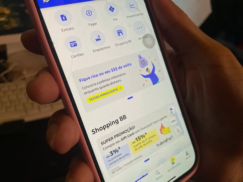 Foto de mão segurando celular com a tela na página inicial do aplicativo do Banco do Brasil