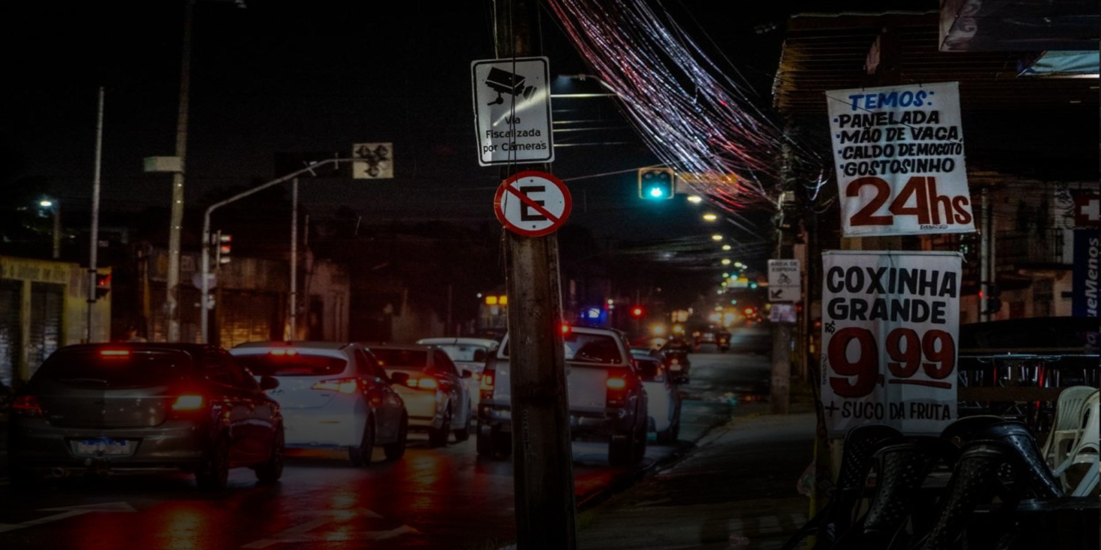 Foto que contém trânsito na avenida Augusto dos Anjos na madrugada. À direita, ofertas de lanches