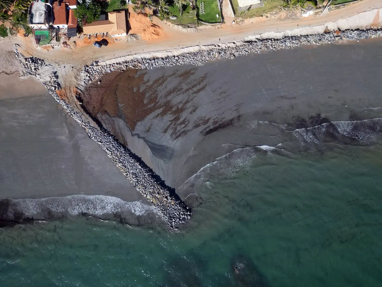 Foto aérea de espigão em construção na praia de Icapuí, no Ceará, perto de estrada de areia