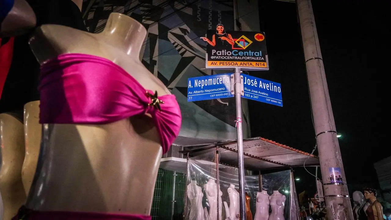 Foto que contém manequim com sutiã rosa. Ao fundo, a placa de identificação do cruzamento da avenida Alberto Nepomuceno com a rua José Avelino