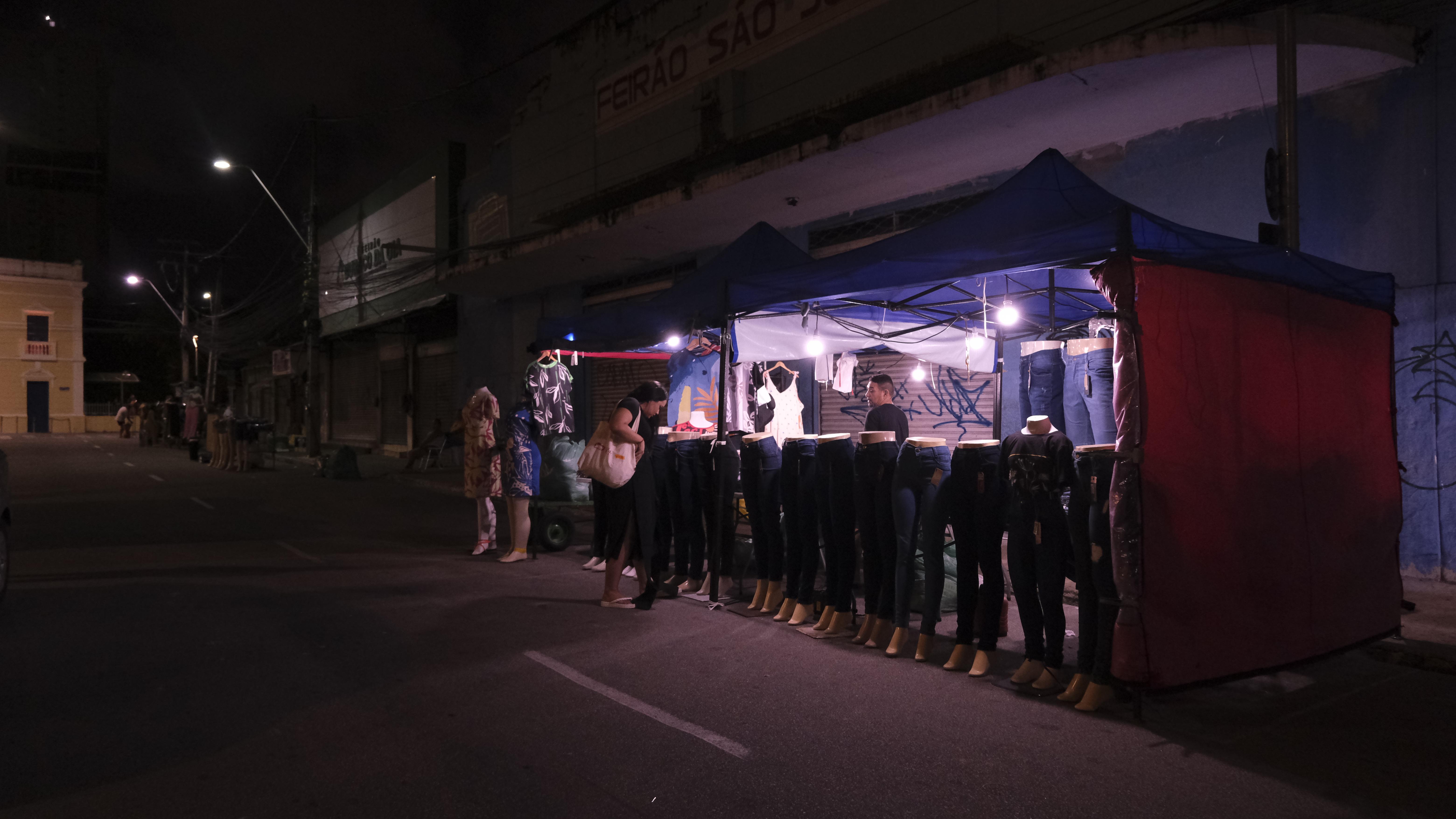 Cliente analisa peças de roupa na Feira da Madrugada