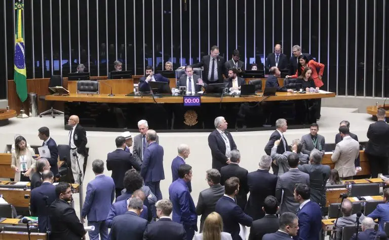 Hugo Motta pauta projeto que revoga aumento do IOF e votação pode ocorrer nesta quarta na Câmara dos Deputados. Sessão da Câmara dos Deputados com parlamentares discutindo e se movimentando na plenária, em ambiente formal com destaque para a bancada brasileira e bandeiras ao fundo.