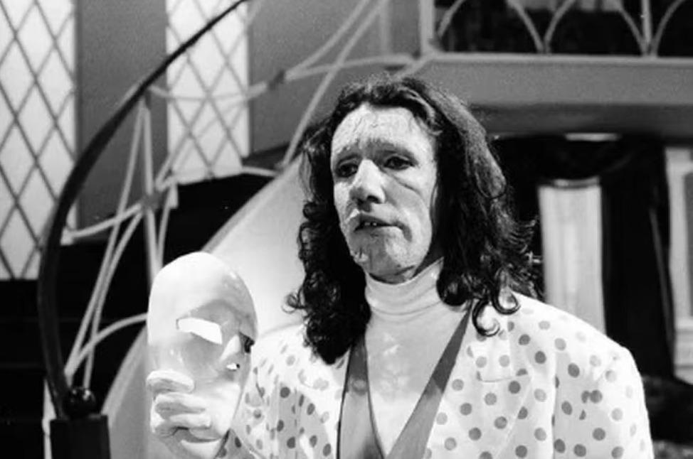 Mascarado em foto preto e branco segurando sua máscara na novela A Viagem