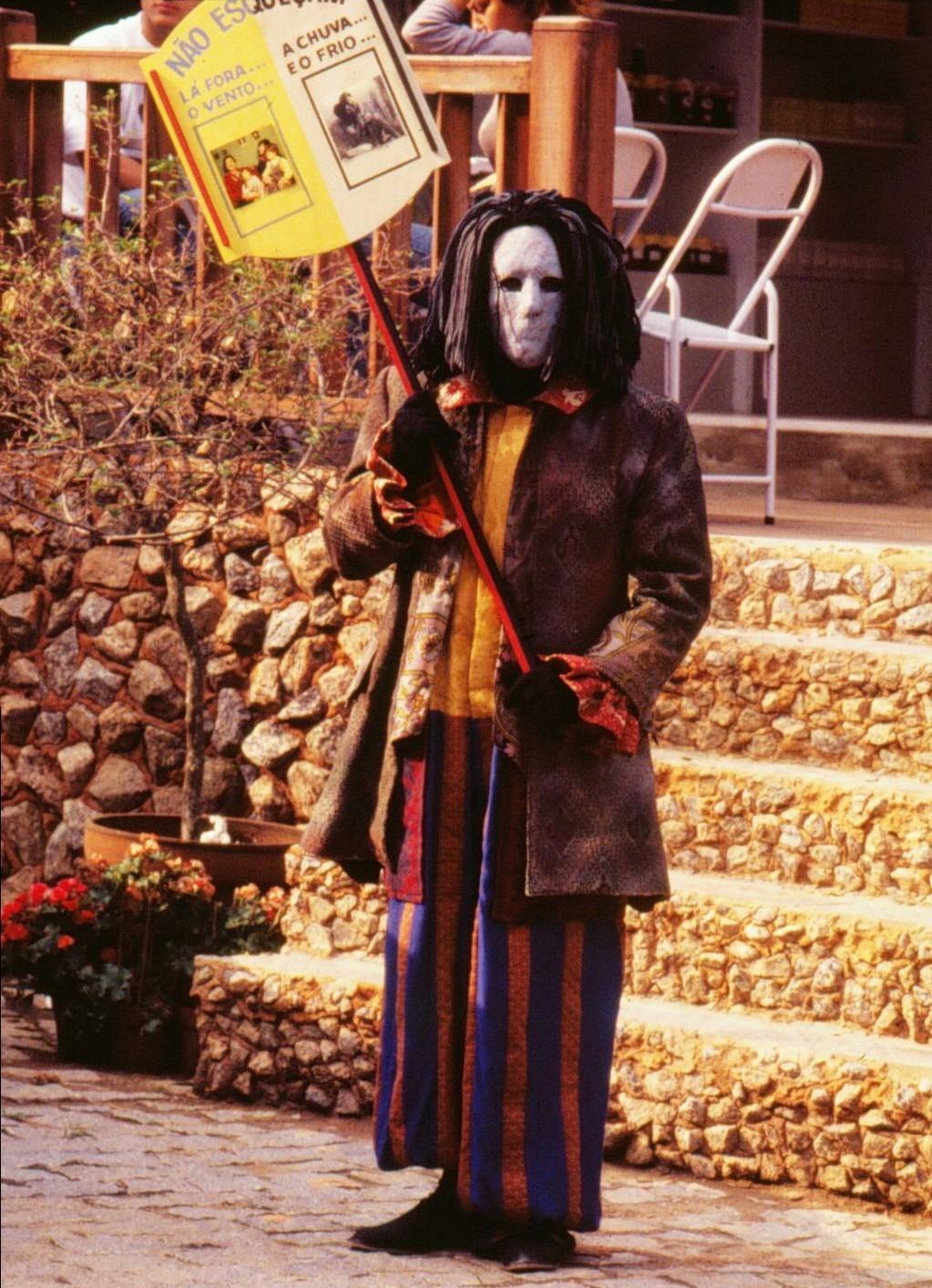 Mascarado segura cartaz em cena da novela A Viagem