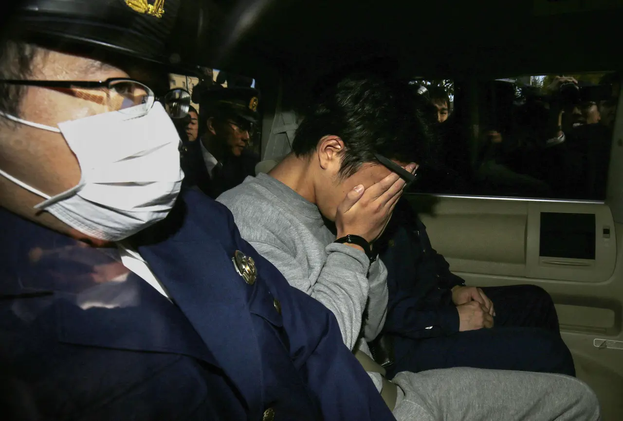 Imagem mostra o criminoso Takahiro Shiraishi, conhecido como Assassino Twitter, cobrindo o rosto no interior de um carro, ilustrando execução dele pela Justiça do Japão após ser condenado a morte por matar 9 pessoas
