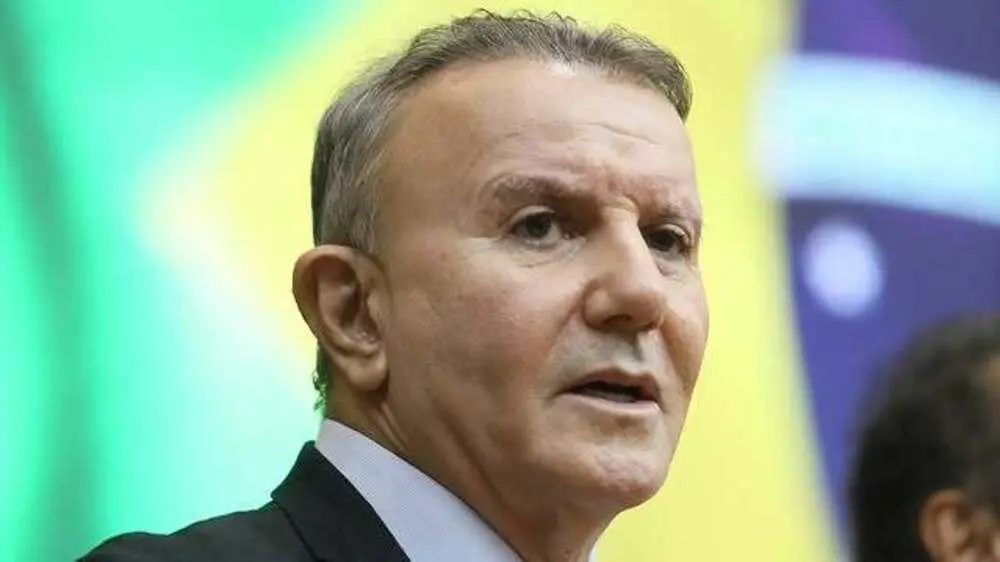 Eduardo Siqueira Campos, homem de meia-idade, vestindo terno escuro e camisa clara, fala em ambiente formal. Ao fundo, há uma bandeira do Brasil desfocada, sugerindo contexto oficial ou político. Imagem usada para informa que politico foi preso suspeito de vazar informações sigilosas do STJ