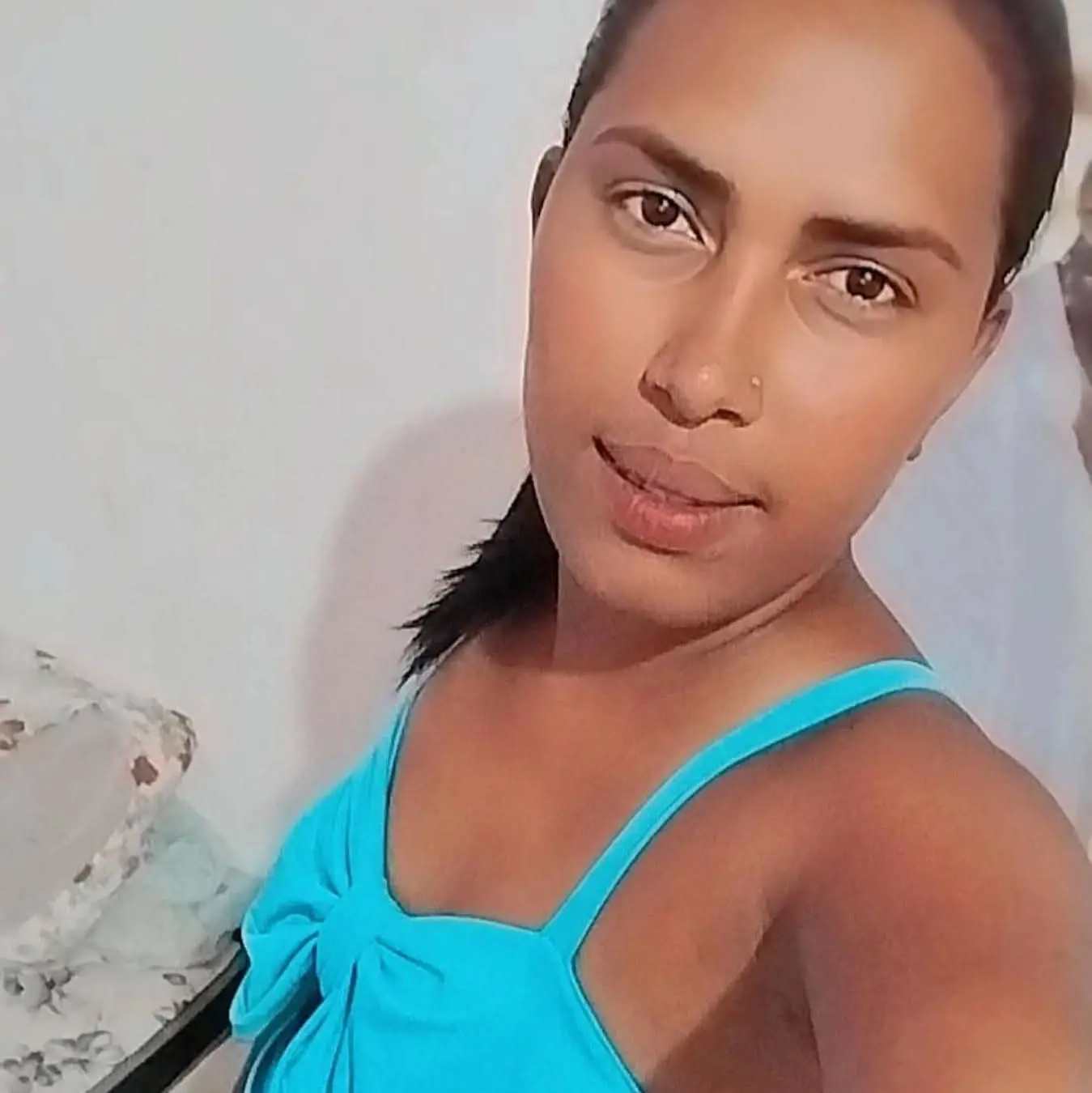 Jessilene tem cabelos pretos amarrados em um rabo de cavalo. Ela é uma jovem negra e, na foto, usa uma blusa de alça azul