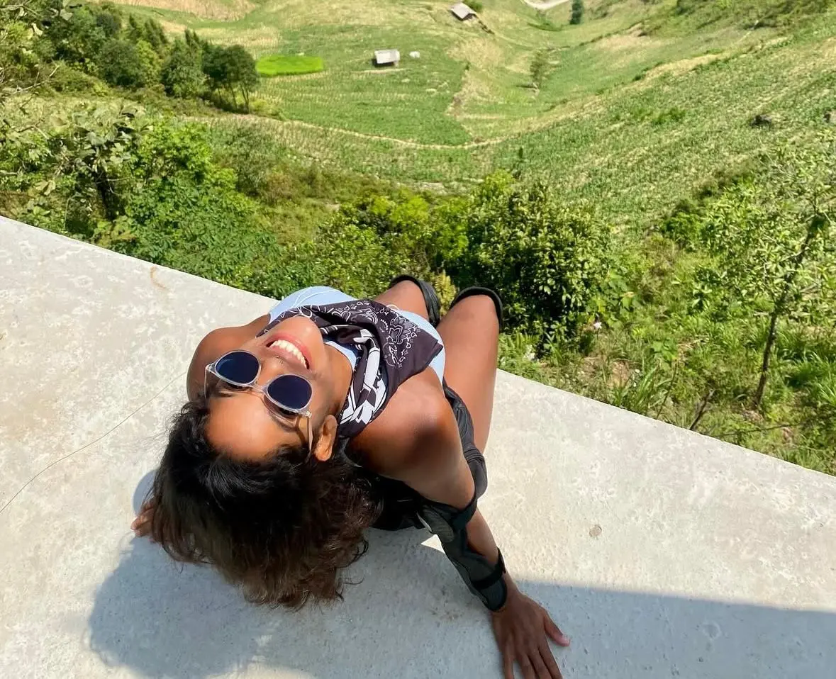 Juliana Marins sentada em um parapeito de frente para uma paisagem deslumbrante na Ásia