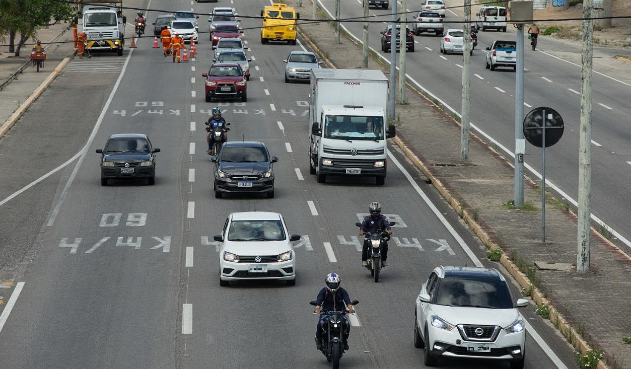 Foto de rodovia larga em Fortaleza com 3 faixas ocupadas por carros, caminhões e motos; no asfalto, há a pintura de velocidade de 50 km/h
