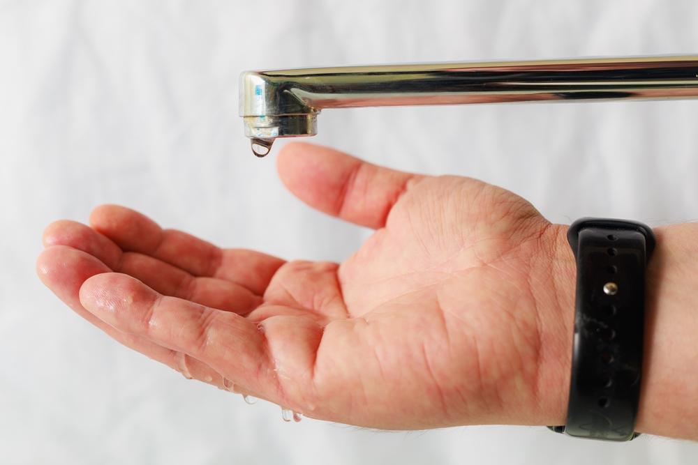 Mão abaixo de torneira caindo um pingo de água