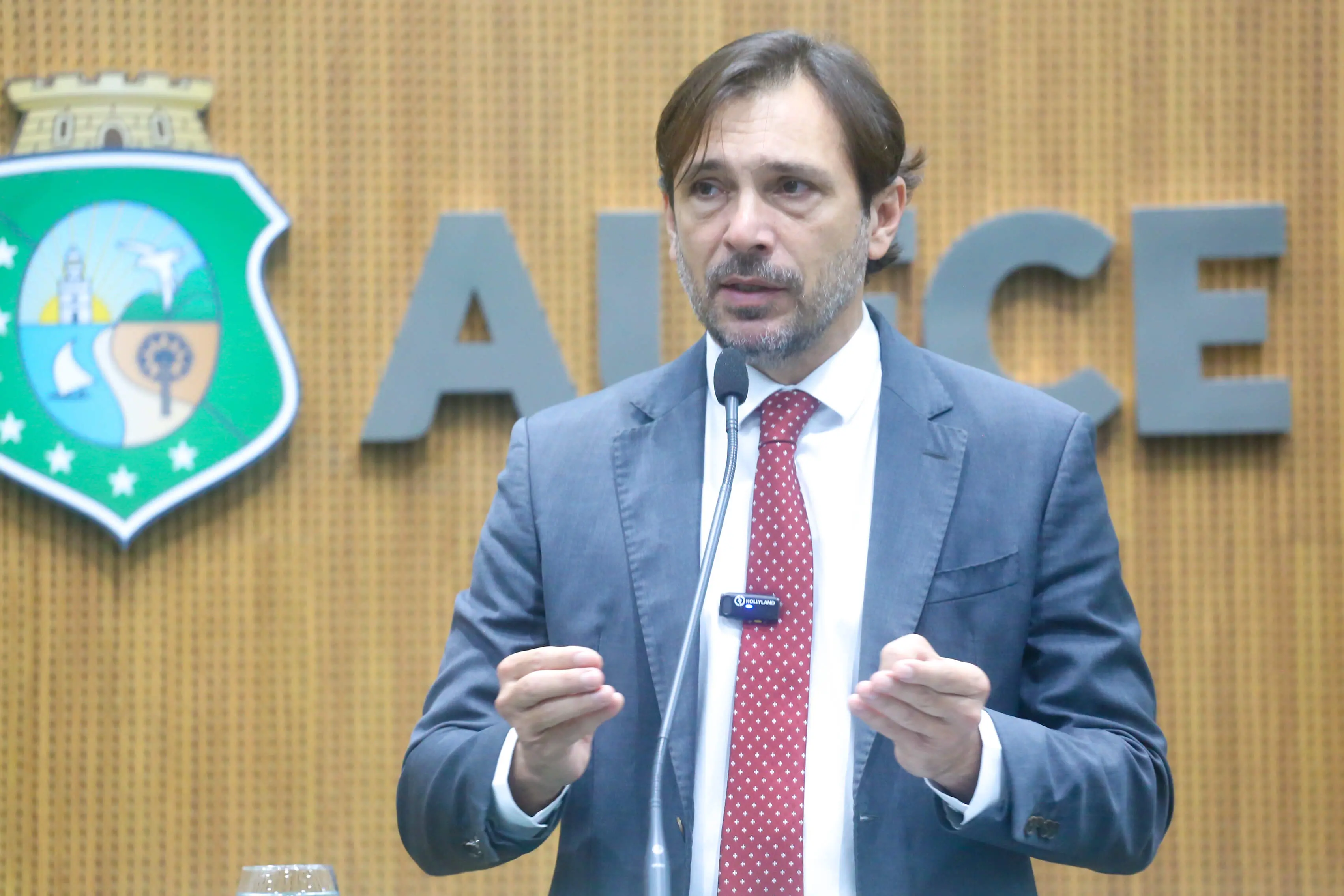 Foto do deputado estadual Guilherme Sampaio, na tribuna da Assembleia Legislativa do Ceará, em que ele aparece ao centro da imagem falando ao microfone