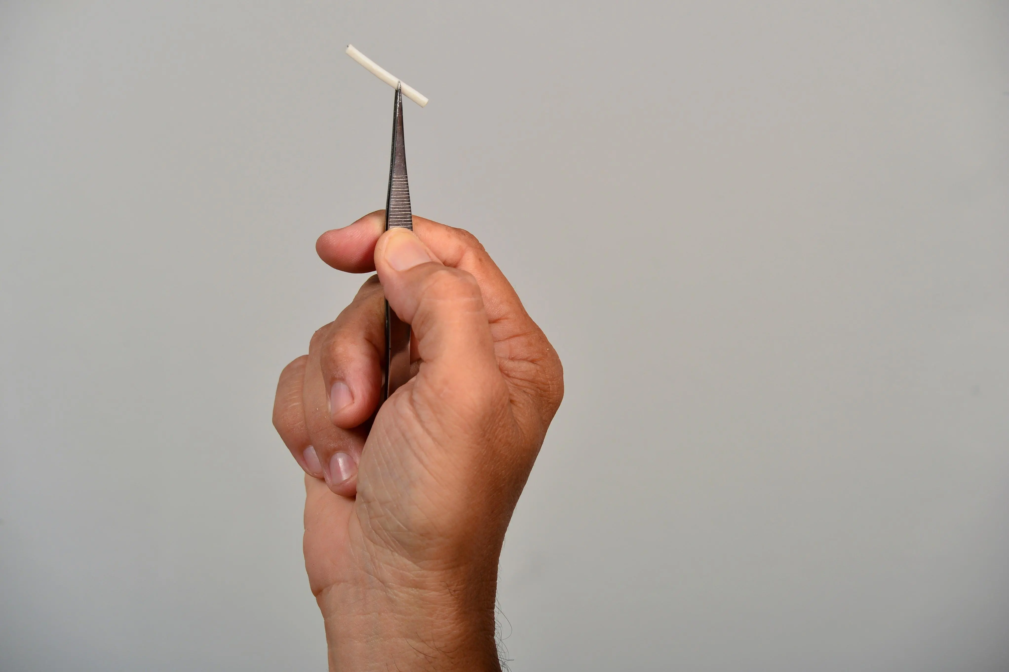 Mão segurando Implanon, também conhecido como implante subdérmico contraceptivo liberador de etonogestrel