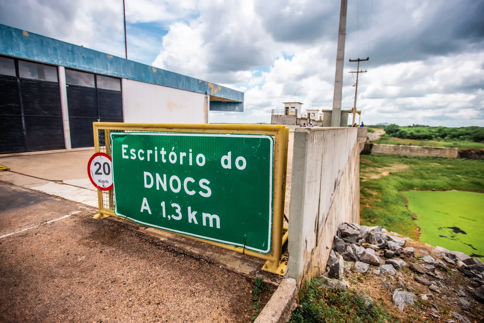 Imagem mostra placa de sinalização indicando presença de escritório do DNOCS a 1,3km do local no Açude Castanhão, no Ceará
