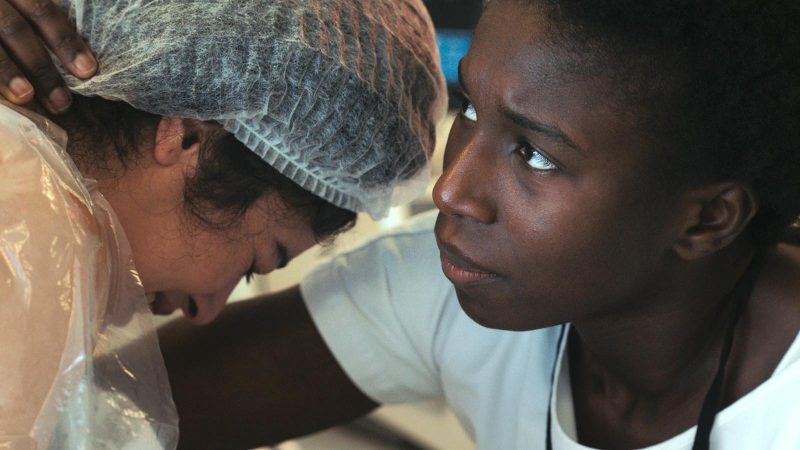 Enfermeira concentrada realizando procedimento de cuidados com paciente durante uma cirurgia.