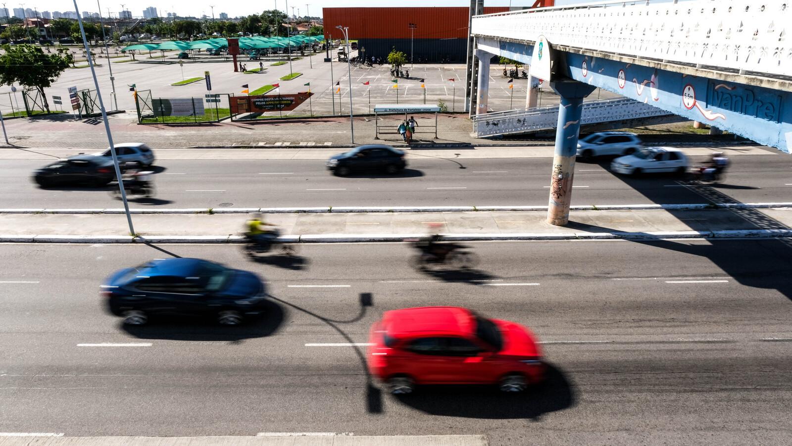 Imagem mostra carros em alta velocidade em avenida de Fortaleza. Os veículos aparecem embaçados na foto.