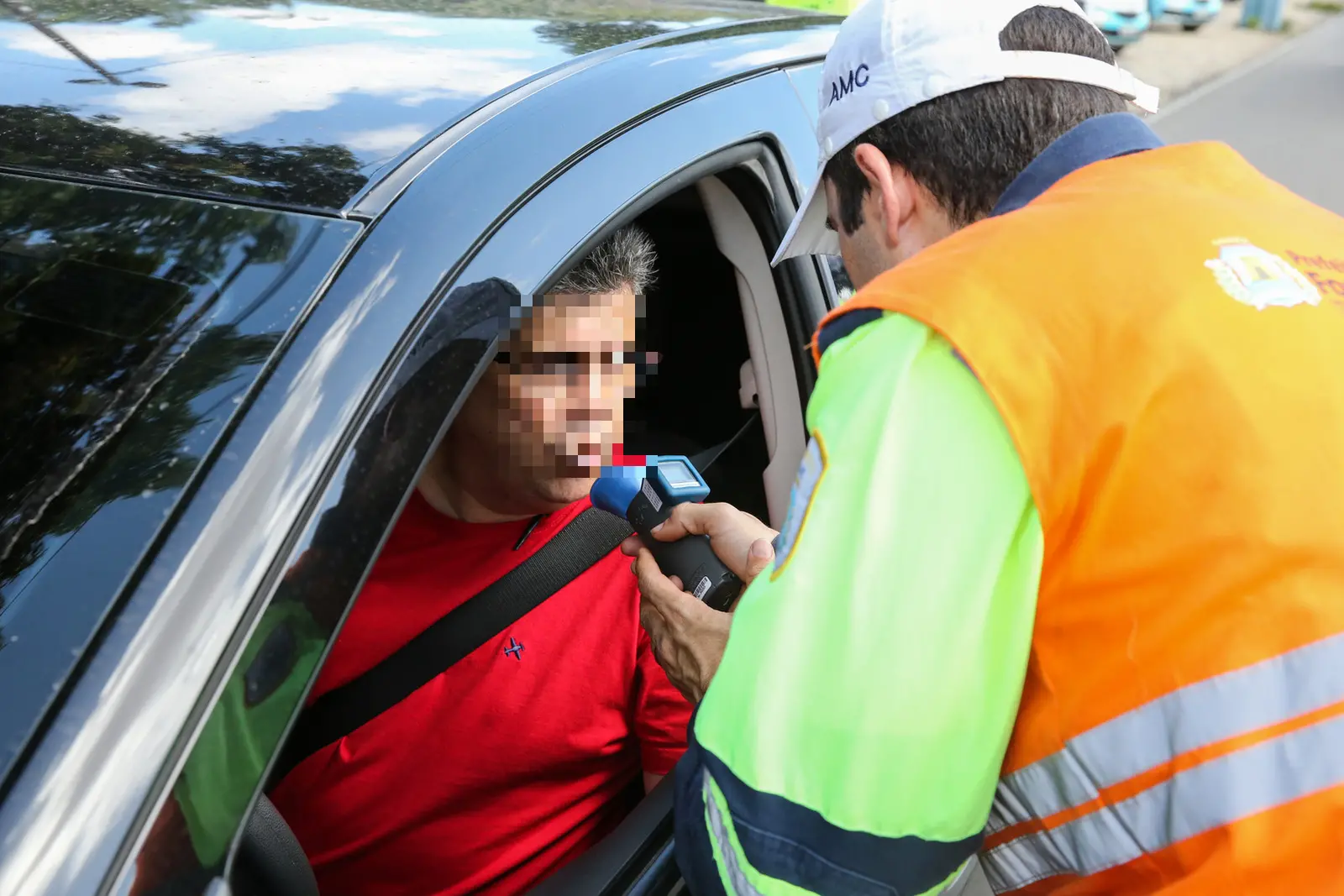 Imagem mostra agente da AMC realizando o teste do bafômetro com um homem dentro de carro em Fortaleza