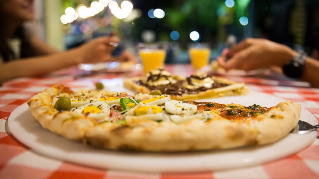 Imagem de família consumindo pizza em estabelecimento de Fortaleza, no Ceará