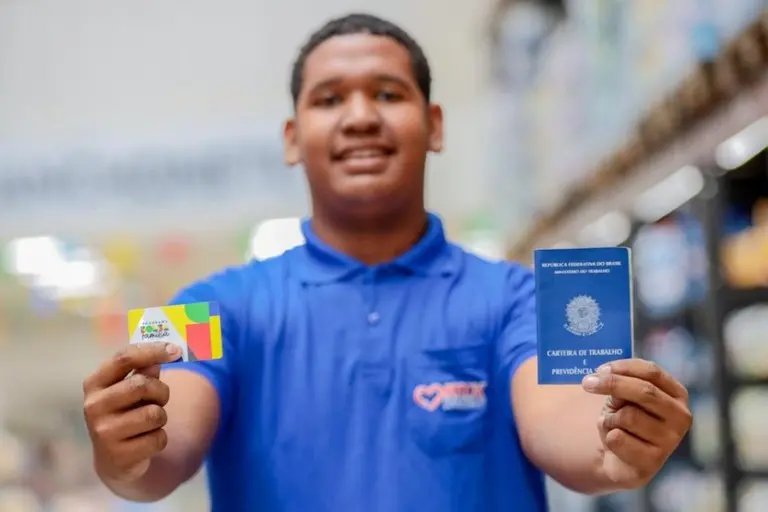 Jovem mostrando o cartão do Bolsa Família e Carteira de Trabalho