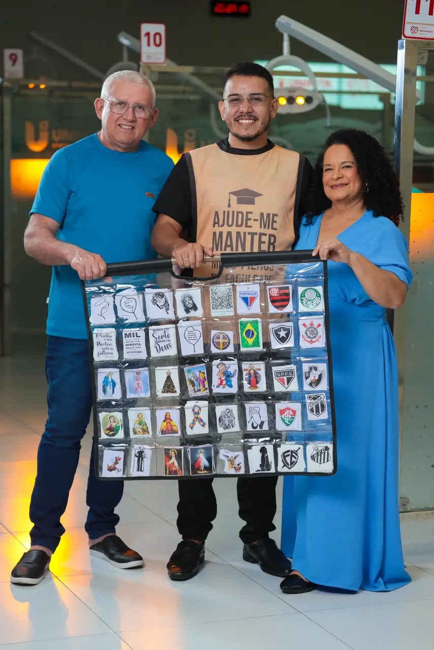 Imagem de Matheus Camelo segurando o catálogo de adesivos junto com os pais