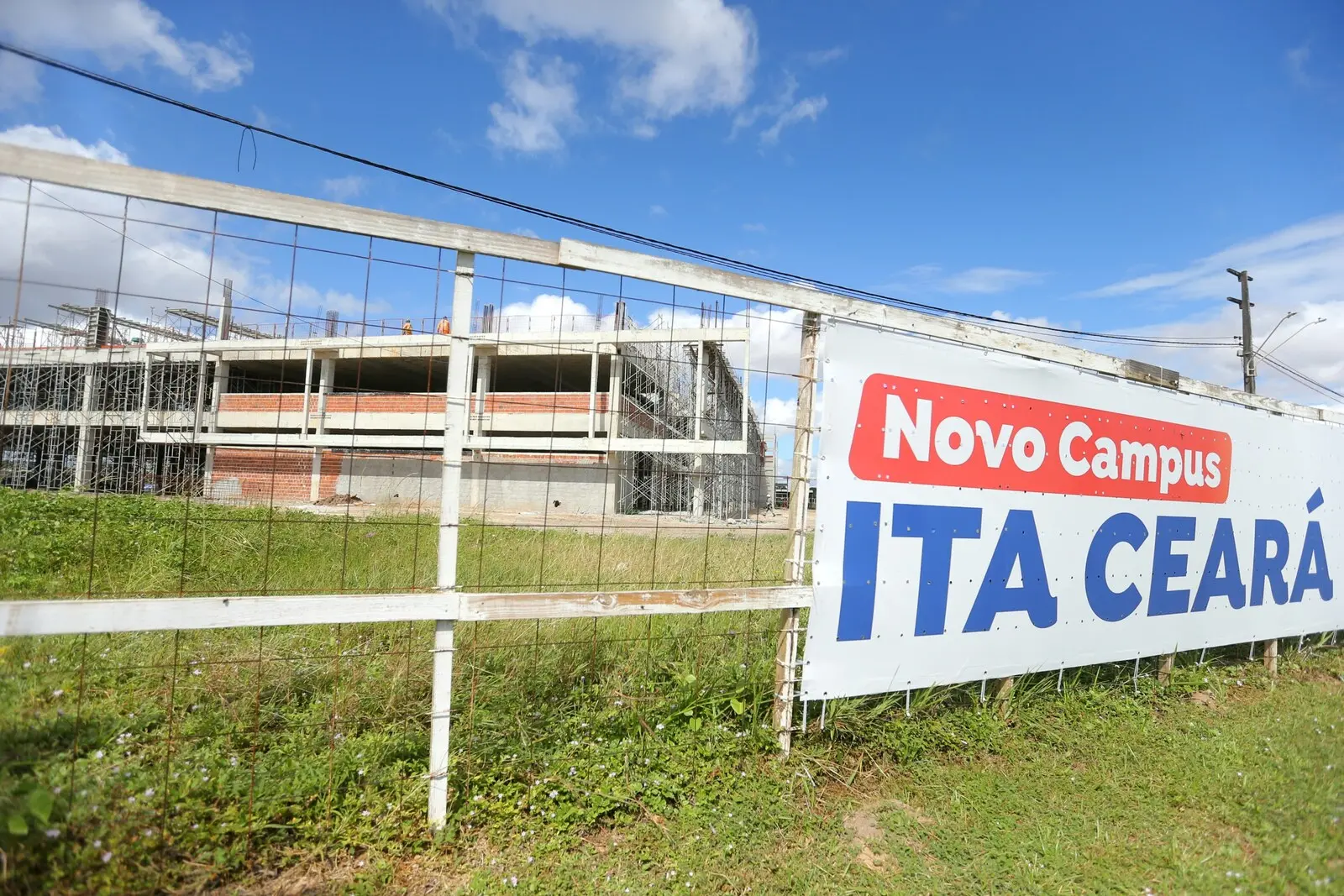 Imagem mostra, em primeiro plano, um banner no qual se lê Novo Campus ITA Ceará. Ao fundo, um prédio em construção, que sediará as instalações do Instituto Tecnológico da Aeronáutica - ITA - no Ceará.