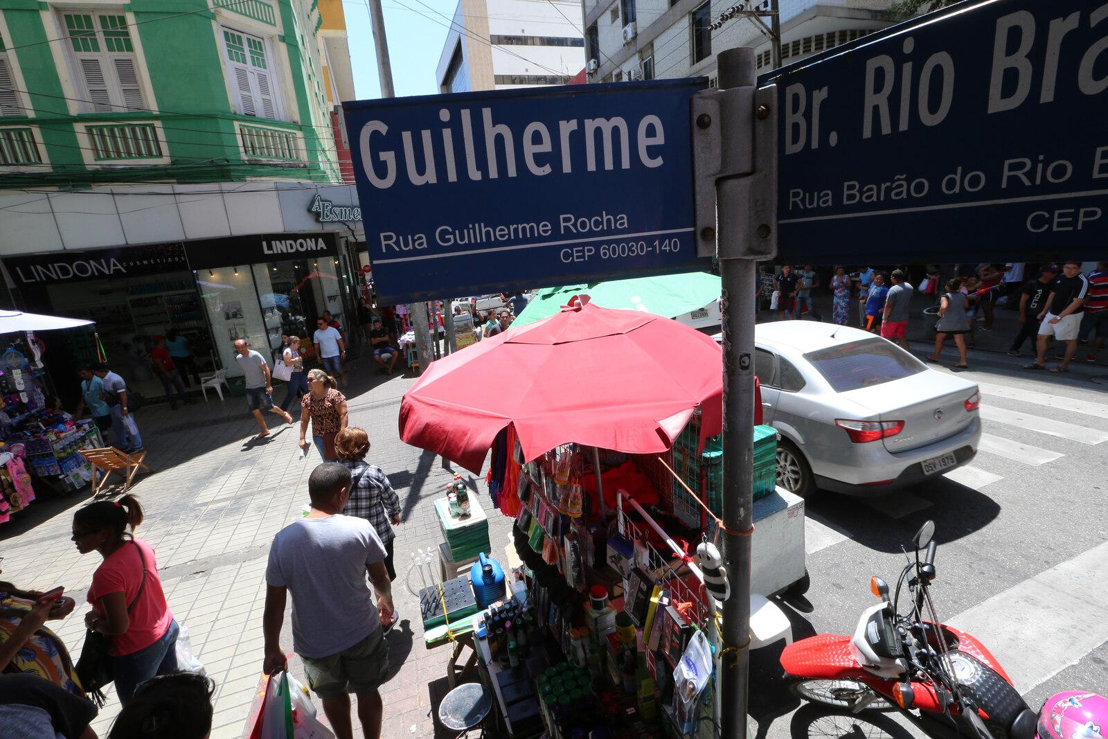 Cruzamento de ruas movimentadas no Centro de Fortaleza, com pessoas e carros