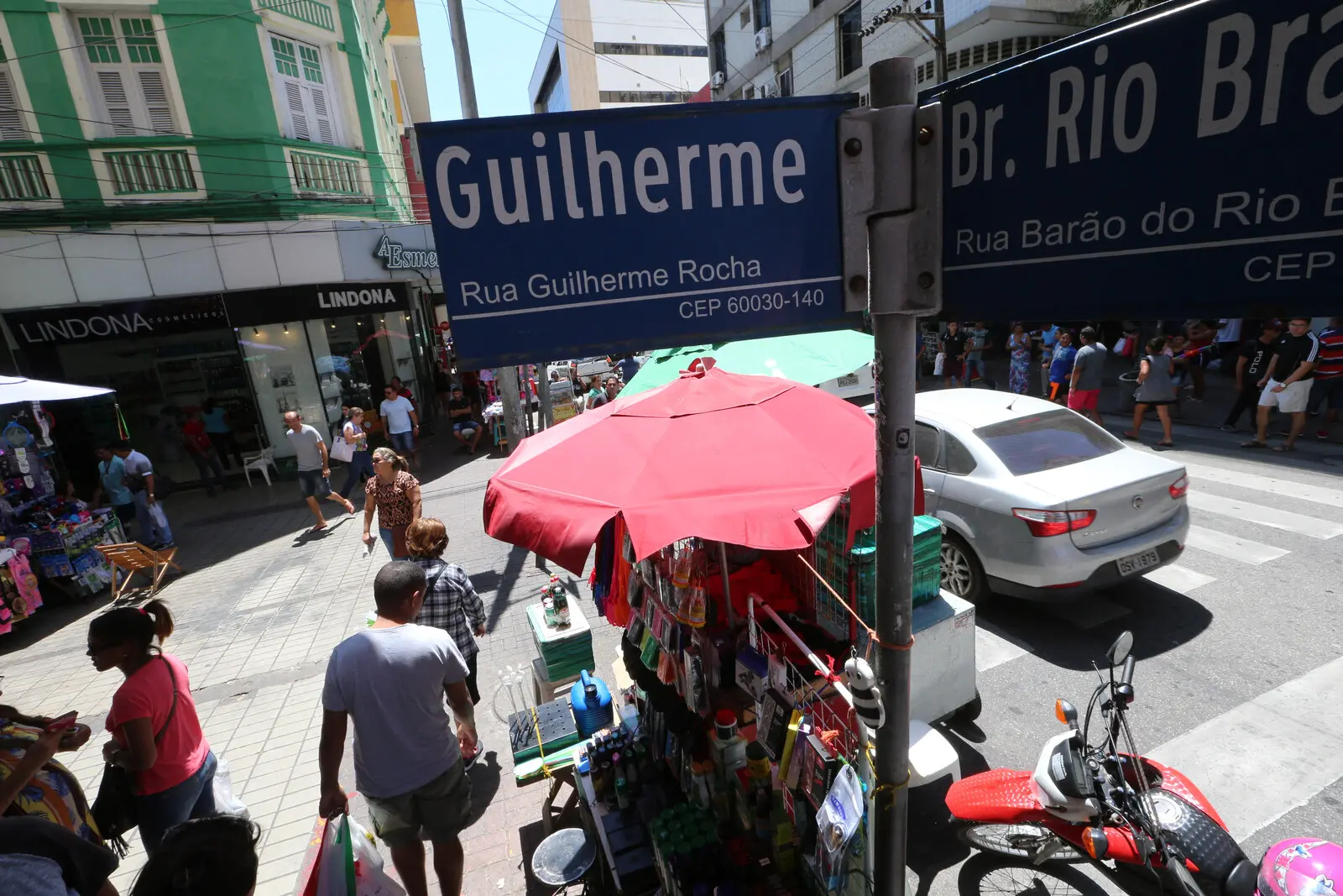 Cruzamento de ruas movimentadas no Centro de Fortaleza, com pessoas e carros