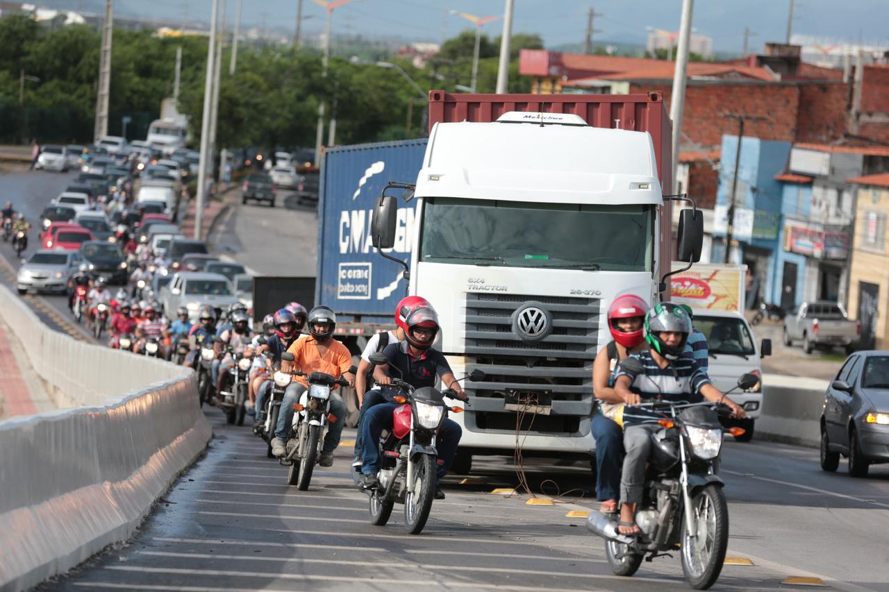 Viaduto movimentado em Fortaleza, com caminhão ao Centro rodeado de motos