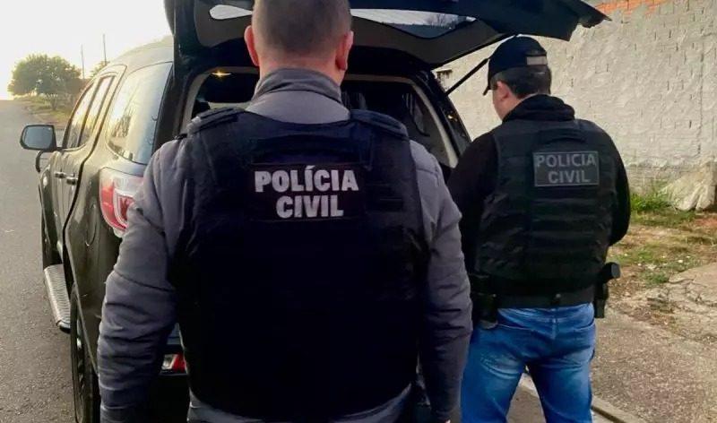 Policiais civis realizando uma abordagem ao lado de um veículo em uma rua, vestindo coletes com a inscrição 'Polícia Civil' em destaque