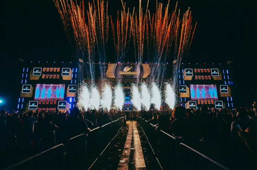 Show de fogos de artifício e luzes em uma festa ao ar livre com público assistindo em um evento de música chamado HaulteLuva, na noite.