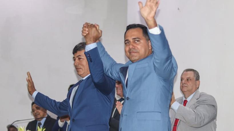 Prefeito e vice de mãos dadas. Dois homens brancos e de terno azul