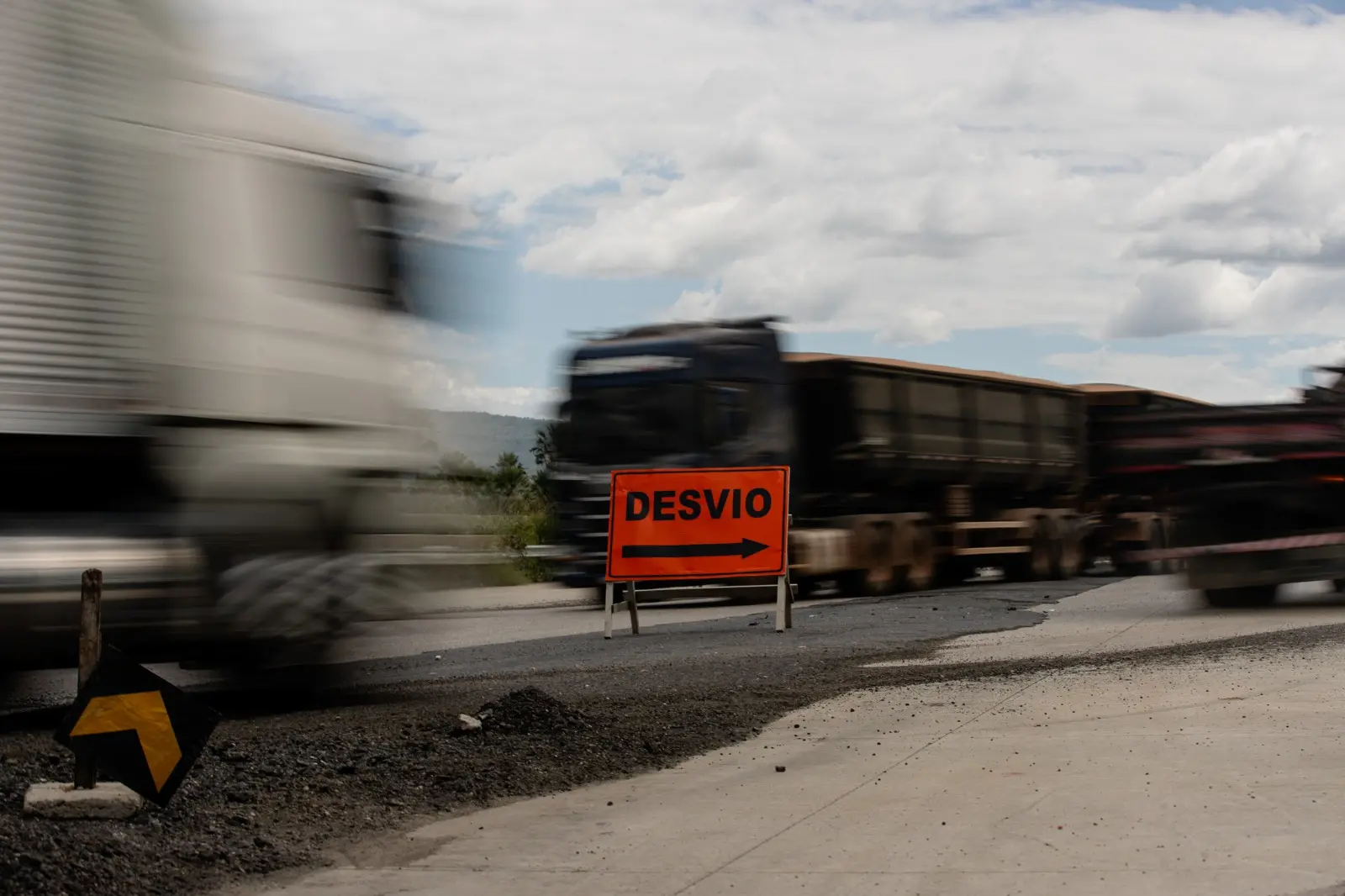 Foto que contém tráfego de caminhões em meio à placa de desvio na BR-222