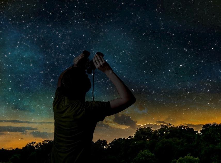 Mulher observa o céu com binóculos