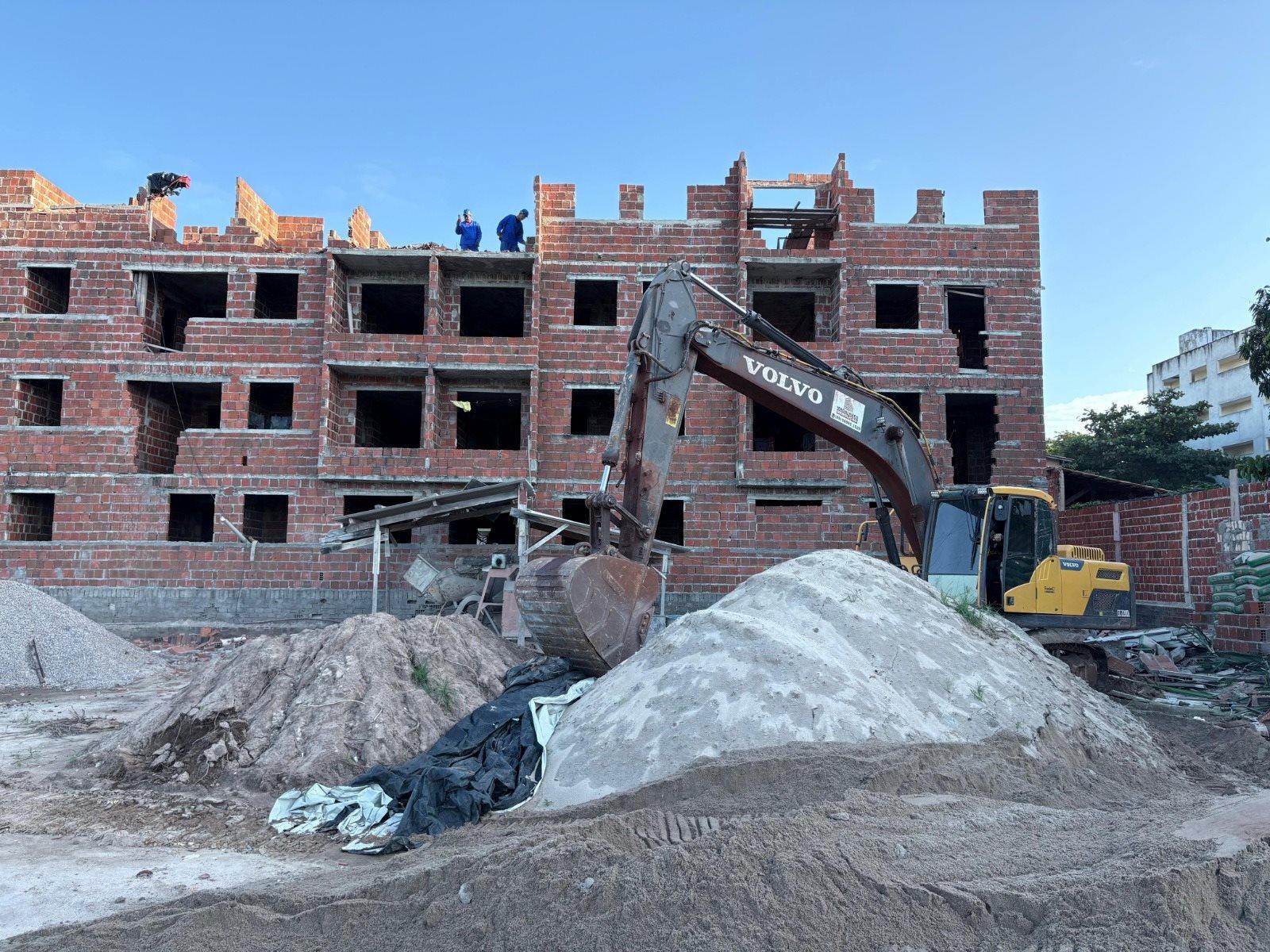 Demolição de edifício residencial com escavadora em obra de construção civil no Brasil