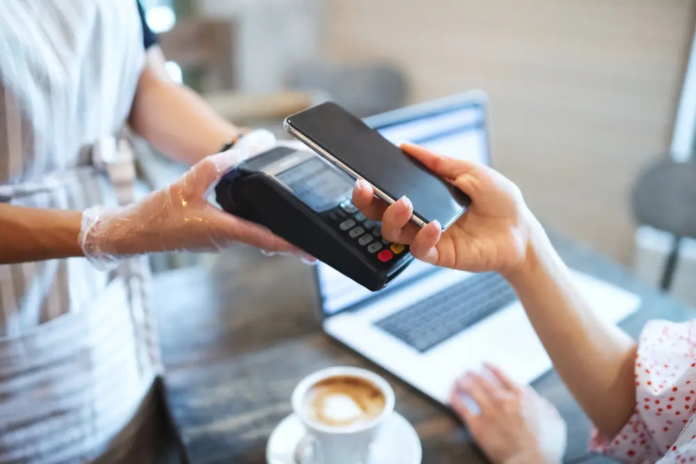 Foto que contém pessoa pagando conta em máquina de cartão