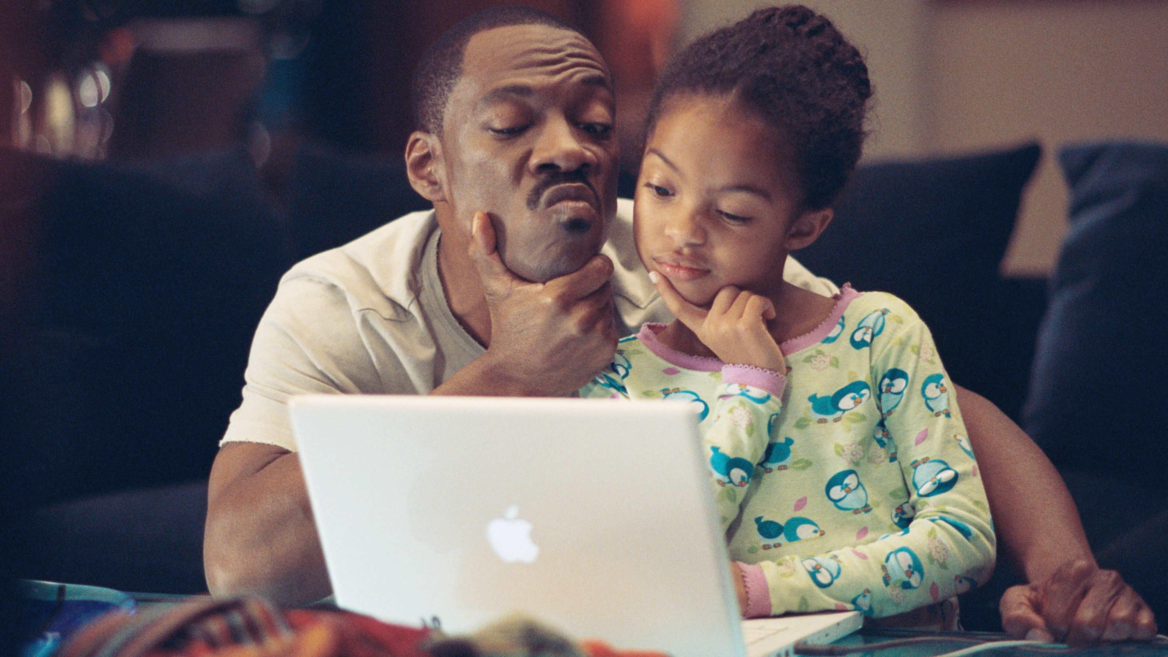 Homem e menina assistindo algo em laptop com expressão de surpresa e curiosidade, sentados no sofá em casa, sugerindo conexão familiar e tecnologia.