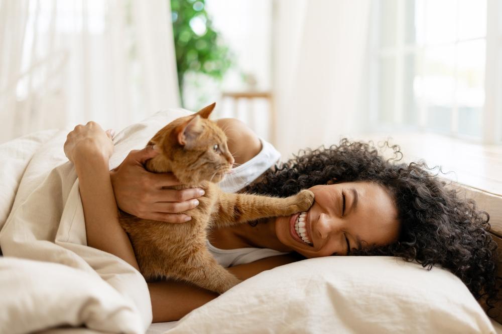 foto de mulher brincando com gato em cama
