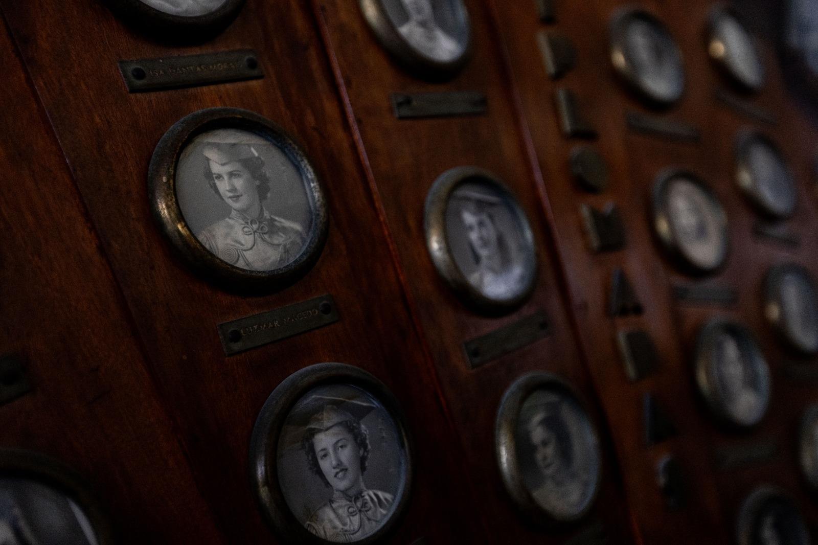 Imagem mostra placa de madeira com miniaturas de fotos de mulheres formadas no Colégio da Imaculada Conceição