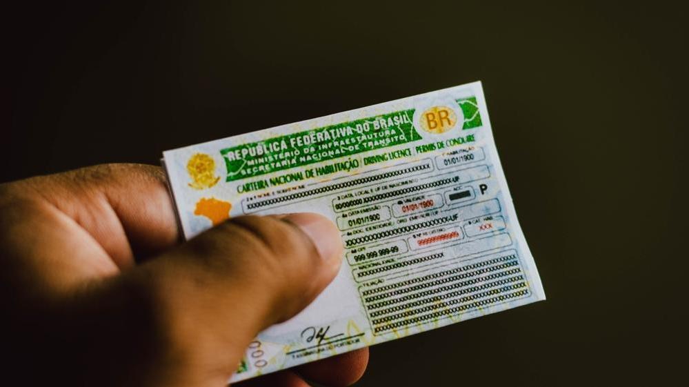 Imagem mostra CNH; uma mão segura o documento