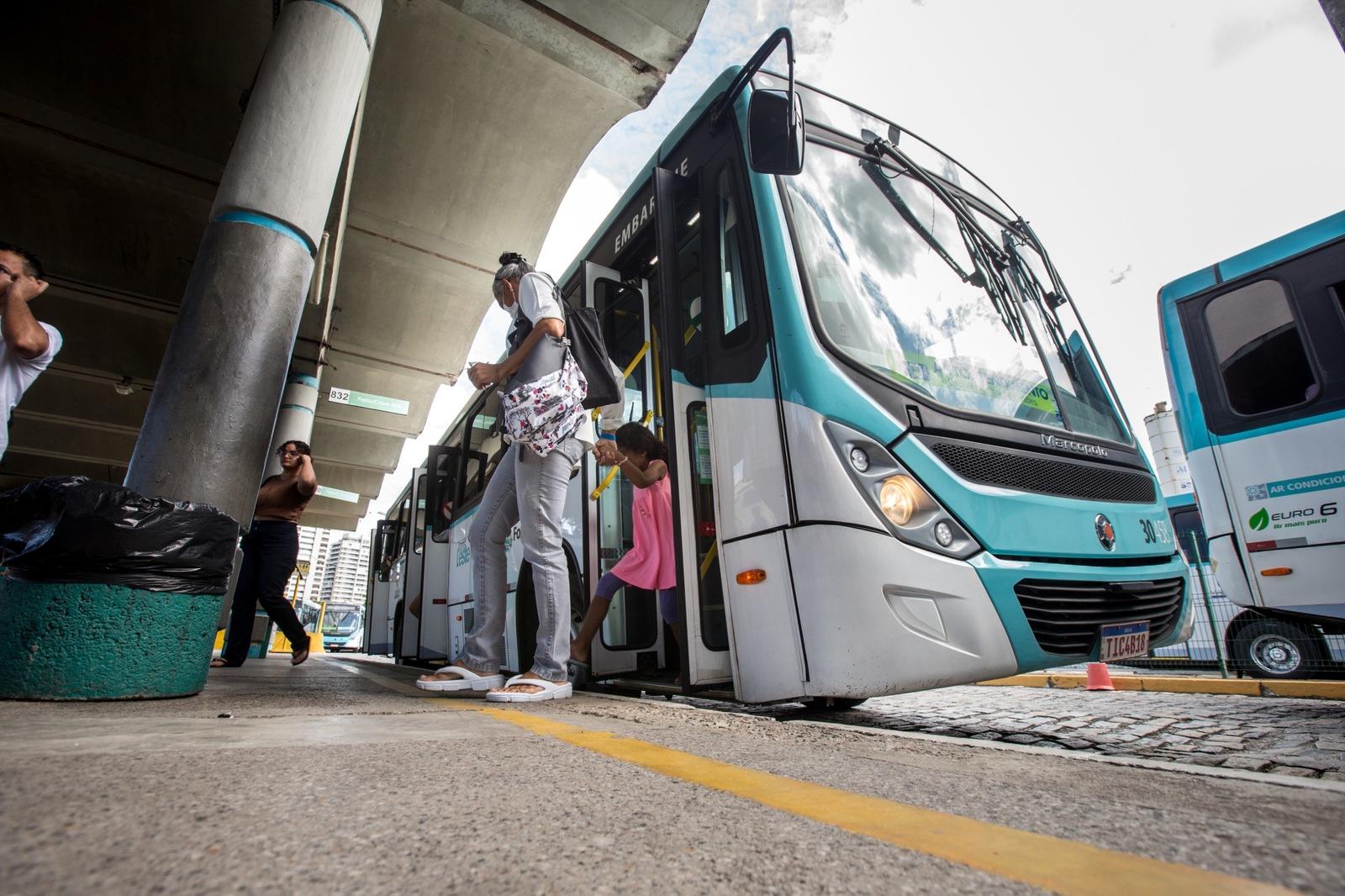 Imagem mostra mulher e criança que descem de ônibus estacionado no Terminal do Papicu, em Fortaleza.