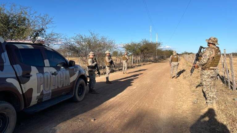 Foto mostra uma composição da Polícia Militar do Ceará em uma estrada carroçável, na divisa do Ceará com outro estado. A imagem mostra cinco policiais militares fardados e uma viatura da PMCE