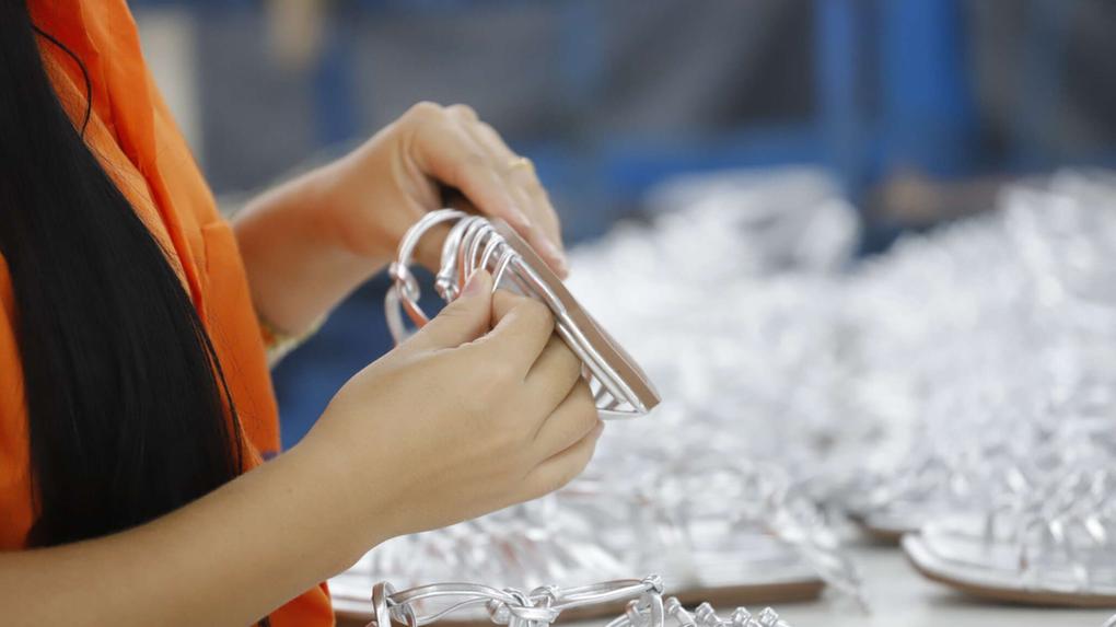 Foto que contém pessoa manipulando um calçado