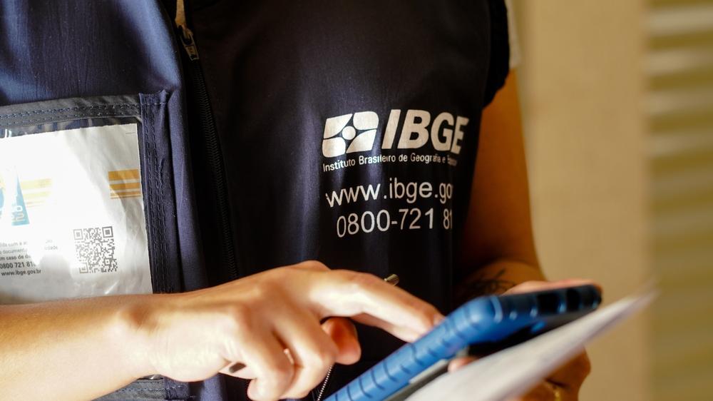 foto de agente do IBGE em visita manuseando o celular.