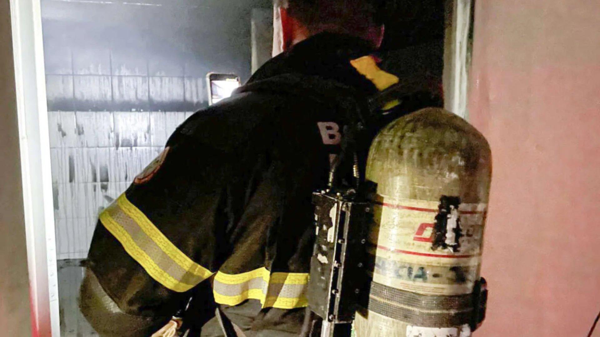 Bombeiro debelando fogo no local da ocorrência, onde homem foi preso por incendiar casa de enfermeira por não aceitar fim do relacionamento