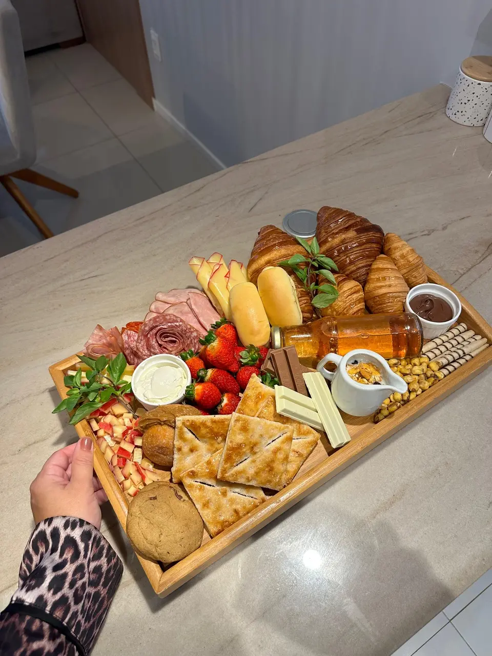 Tábua de comidas espalhadas. Grazing board reúne pães, mel, morangos, chocolate, queijos, presunto e mais ítens coloridos